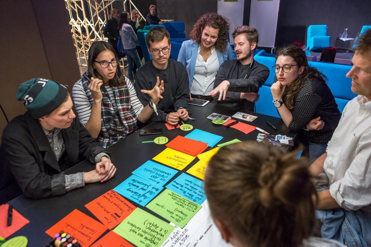 People discussing at a table. Index cards lie in front of them.
