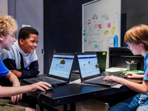 Drei Jugendliche sitzen an zwie Laptops und bauen in einem graphischen Programm Formen.