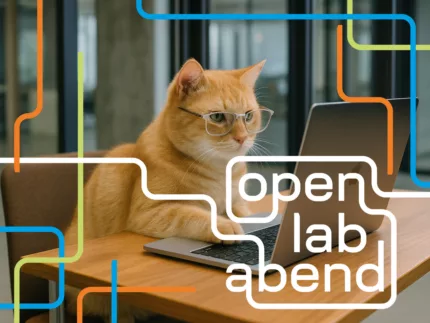 Eine Katze sitzt vor einem Laptop. Sie trägt eine Brille.