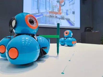 Zwei kleine, runde und blaue Roboter auf einem Tisch.