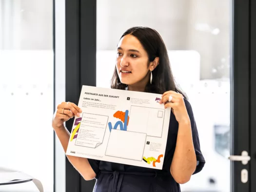 Ein Mädchen hält eine überdimensionierte Postkarte hoch