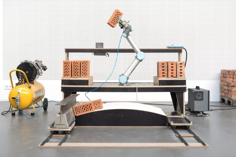 Roboterarm, der Ziegel auf eine gebogene Fläche stapelt.