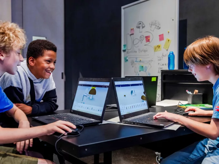 Drei Jugendliche sitzen an zwie Laptops und bauen in einem graphischen Programm Formen.