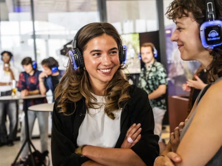 Zwei Frauen stehen nebeneinander. Sie beide tragen Kopfhörer