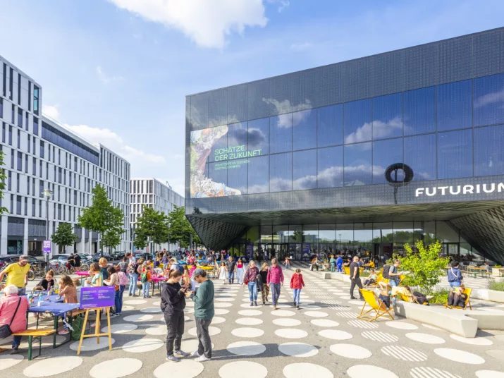 Vorplatz des Futuriums. Menschen tummeln sich auf dem begrünten Vorplatz.