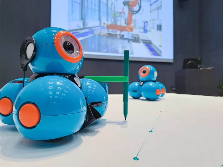 Zwei kleine, runde und blaue Roboter auf einem Tisch.