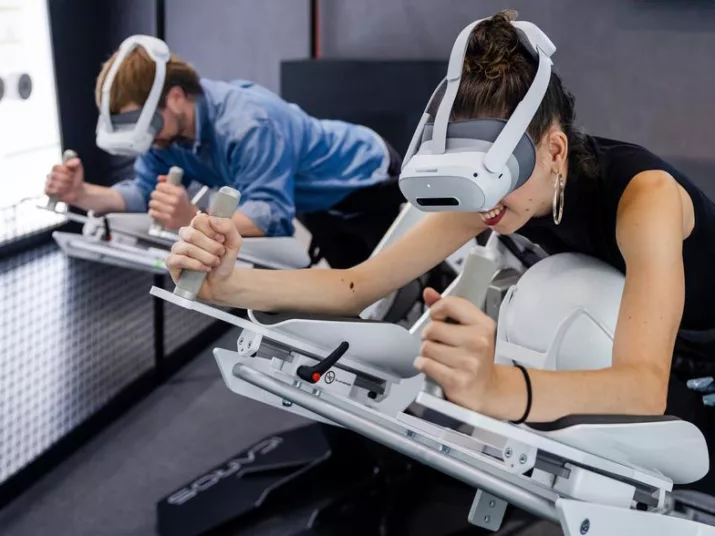 A man and a woman are lying on a technical device wearing VR goggles.